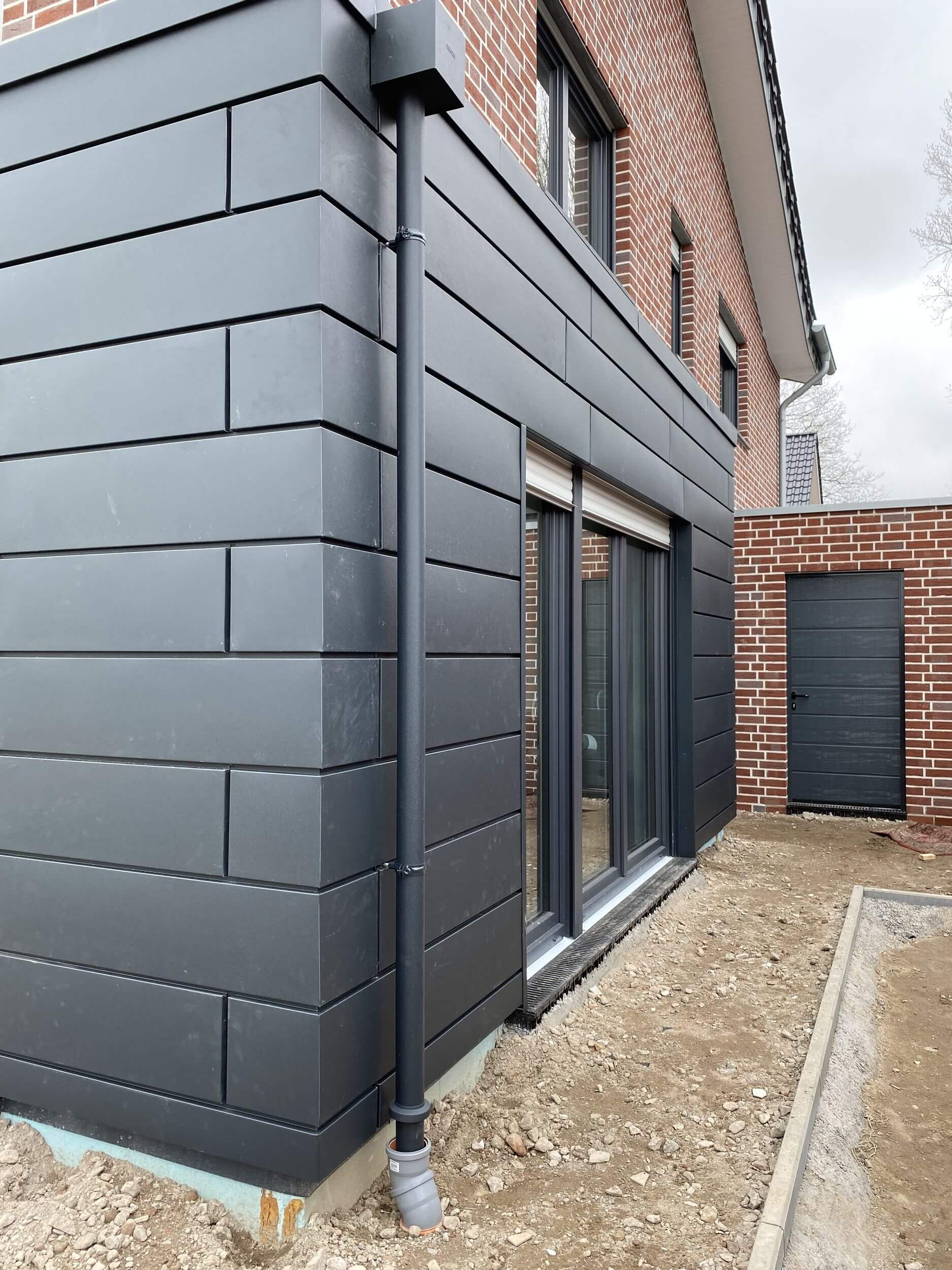 eine dunkelgraue Hauswand mit Terrassentür