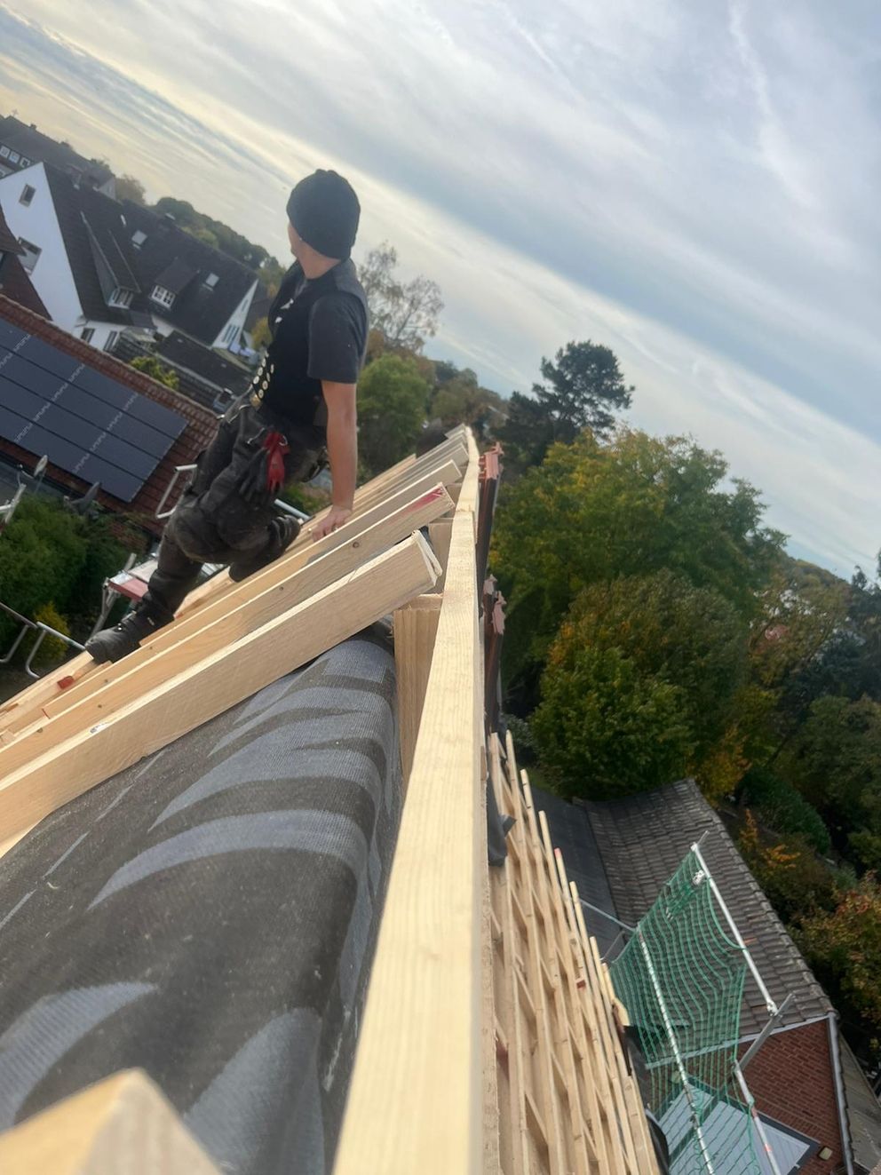 Ein Mitarbeiter steht auf einer Dachspitze und schaut in die Ferne